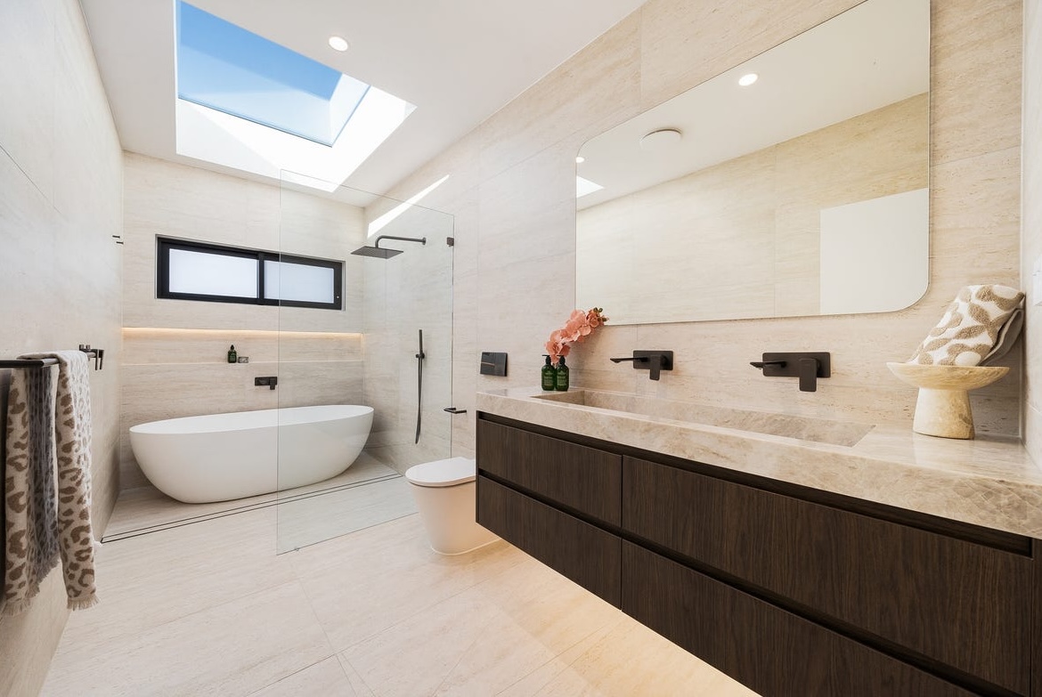 Skylit bathroom with a freestanding bath and timber double vanity