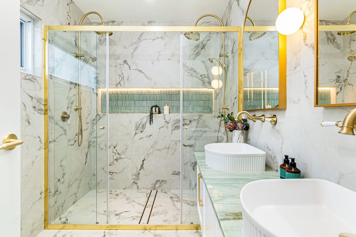 Gold-framed shower screen against marble tiling